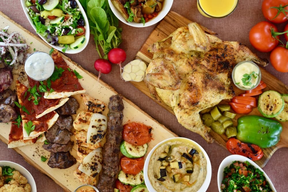 different Mediterranean dishes on a table, including grilled meats and vegetables