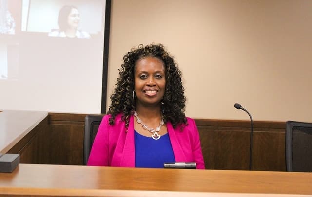 a woman wearing a pink jacket and blue shirt
