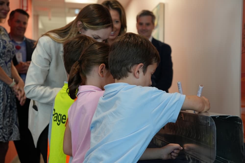 An image of some of a Ronald McDonald House family signing the piece of the new house's door. 