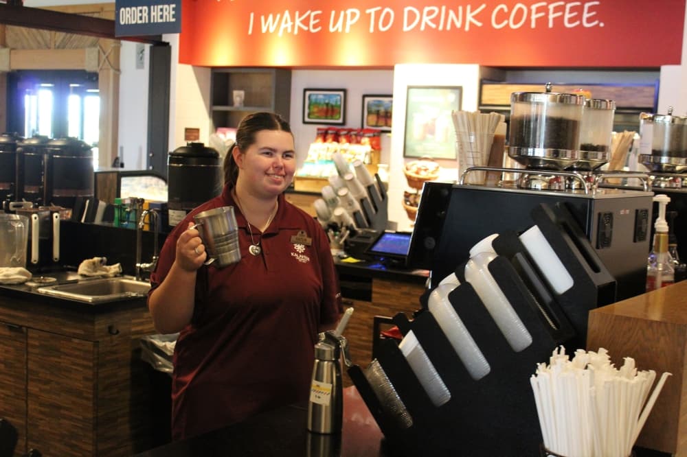 A woman holds a coffee cup in a coffee shop