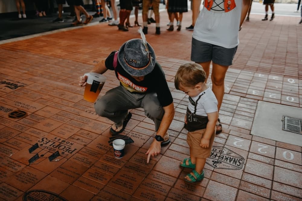 A man points out a brick on a sidewalk to a child at Wurstfest.