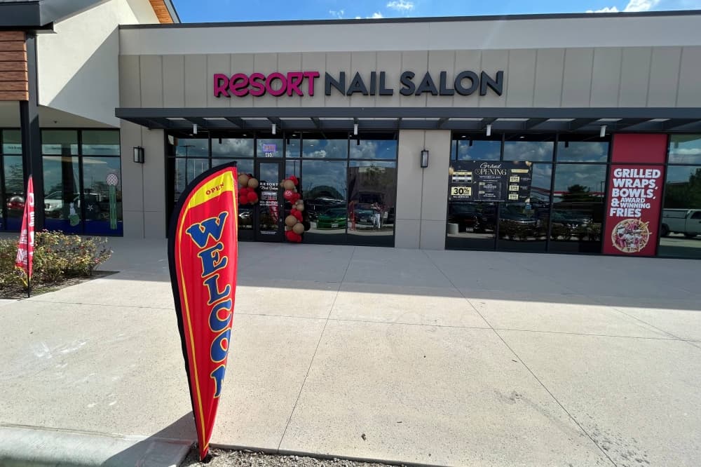 Exterior of a strip mall featuring Resort Nail Salon building signage. 