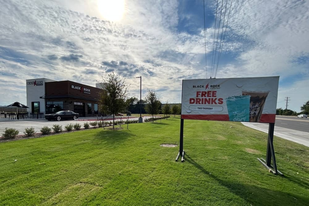 A temporary sign reads Free Drinks this Thursday is posted in front of a Black Rock Coffee Bar store. 