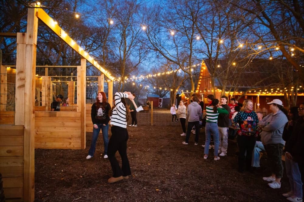 People throwing axes at an outdoor axe throwing lane. 