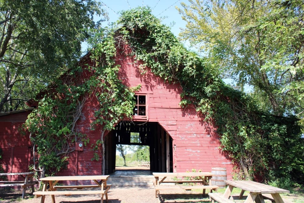 Old red barn with picnic tables sitting outside. 
