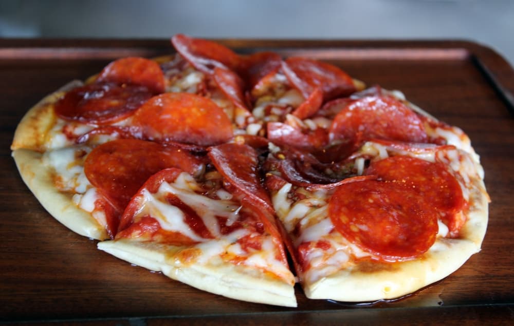 Pepperoni pizza on a wooden tray. 
