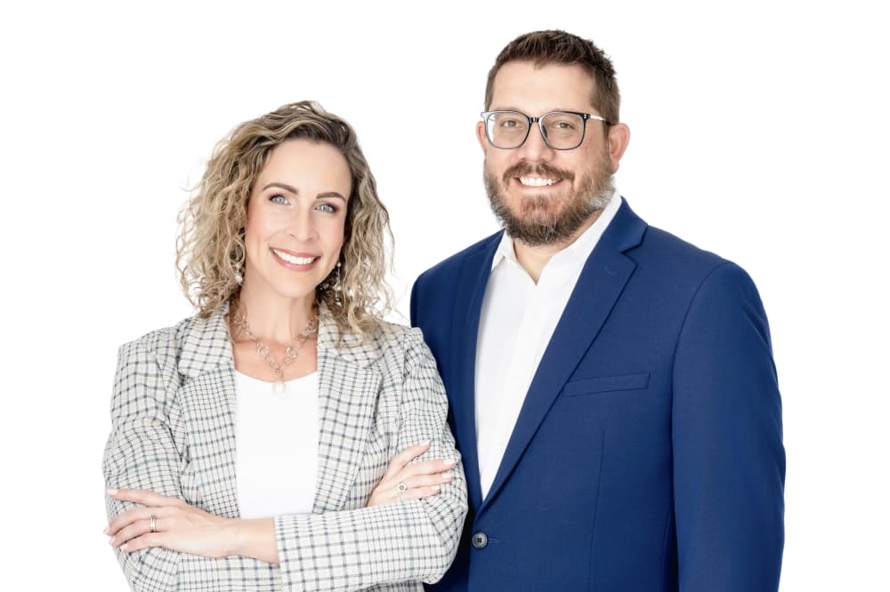 a blonde woman wearing a gray blazer next to a man wearing glasses and a blue blazer