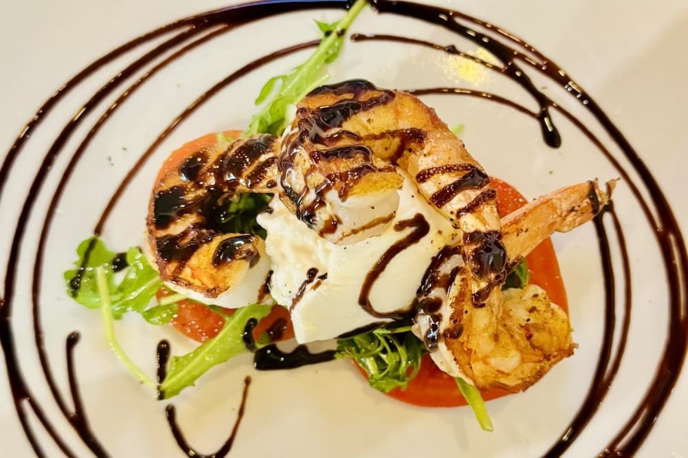The shrimp burrata ($12) includes three grilled shrimp with fresh burrata cheese, tomato, and arugula with a balsamic reduction. (Courtesy Welcome to the Oscar's)