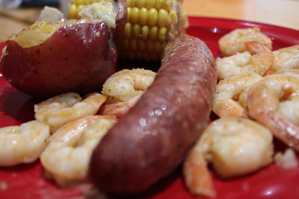 A plate with red potato, corn, sausage and shrimp.