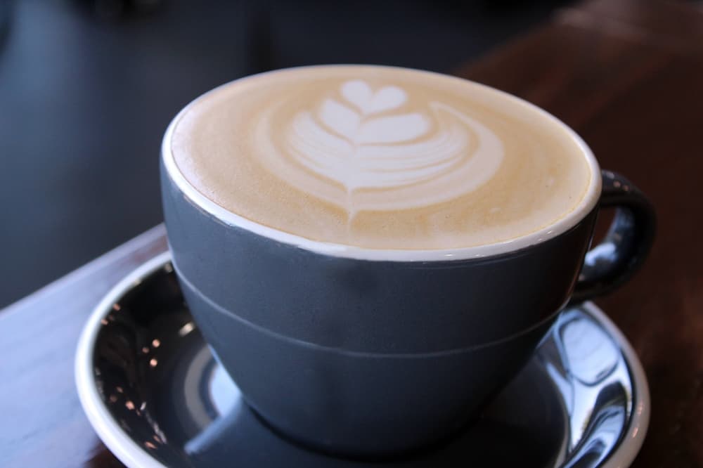 Cup of coffee topped with leaf foam art. 