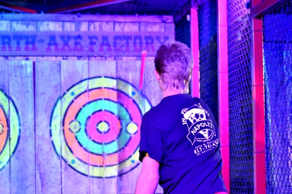 A man throwing an axe under neon lights 