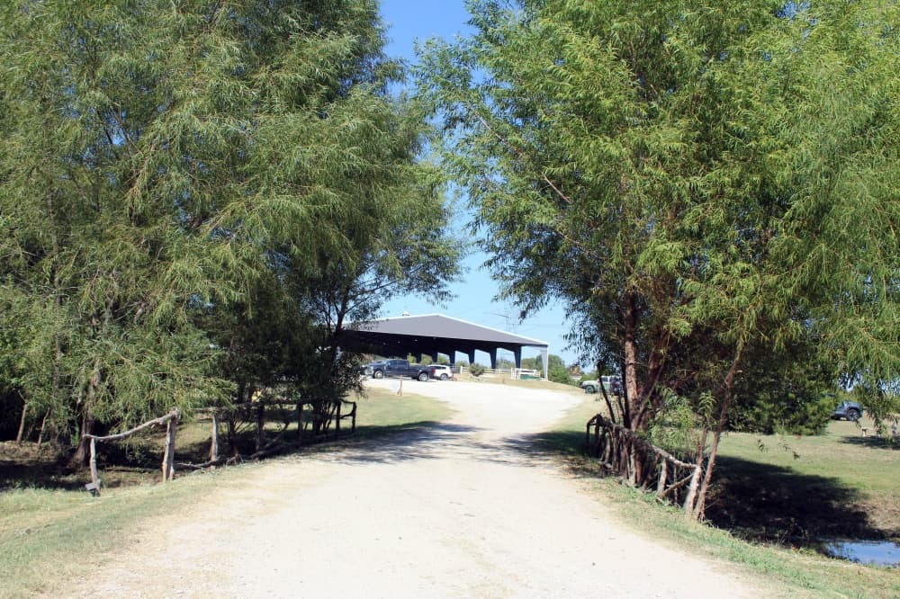 Path through trees leads to a covered arena. 
