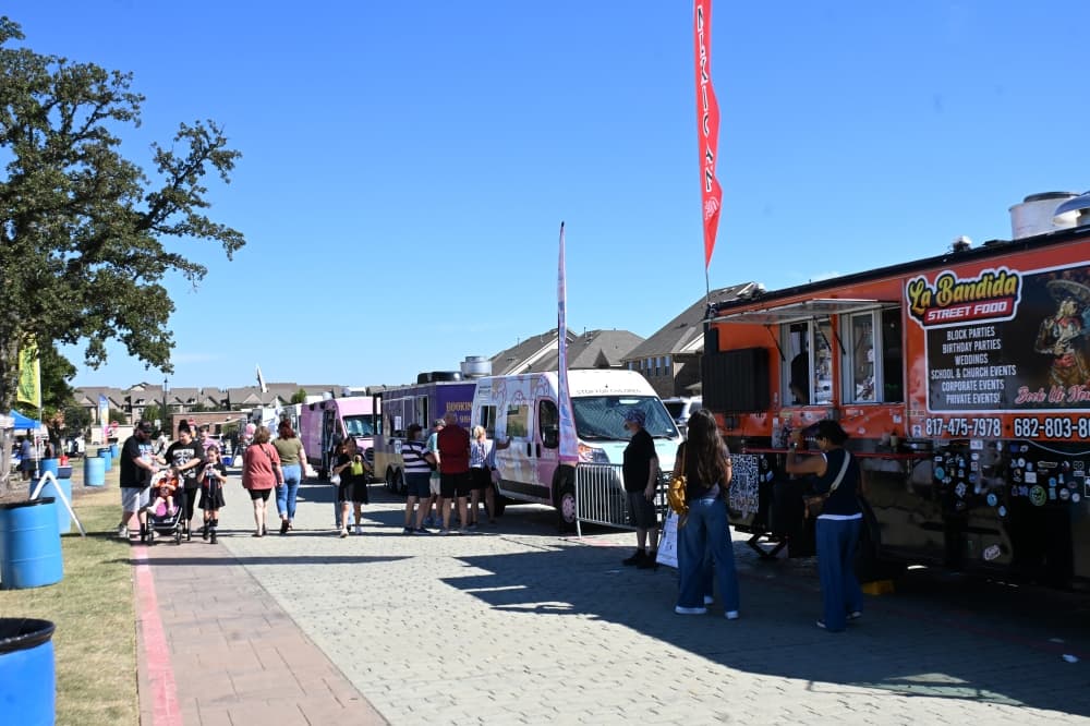 food trucks line a street as people walk around