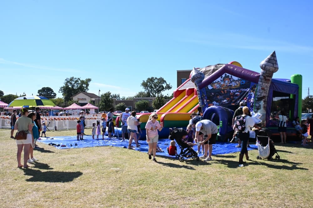 Families gather around bounce houses while their children play in them.