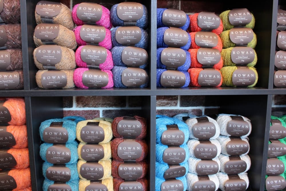 Skeins of different colored yarn displayed in on store shelves. 