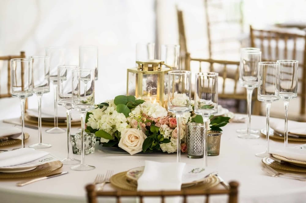 A table with wine glasses and floral decorations.