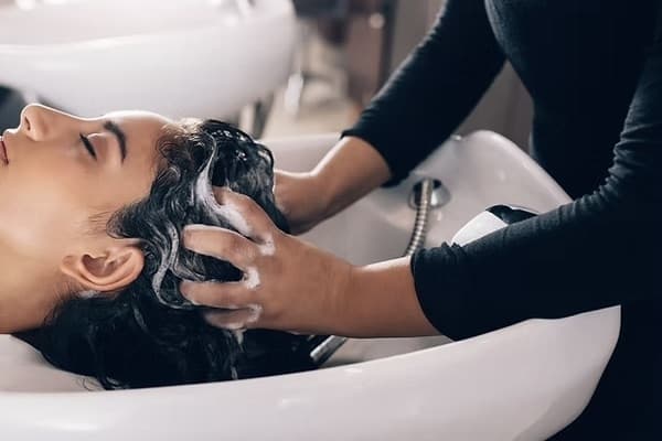 hands washing a woman's hair at a salon station