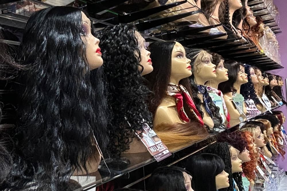 Side view of various wigs displayed on mannequin heads in a store. 