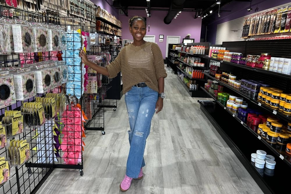 Female standing in a retail store between shelves displaying beauty products. 