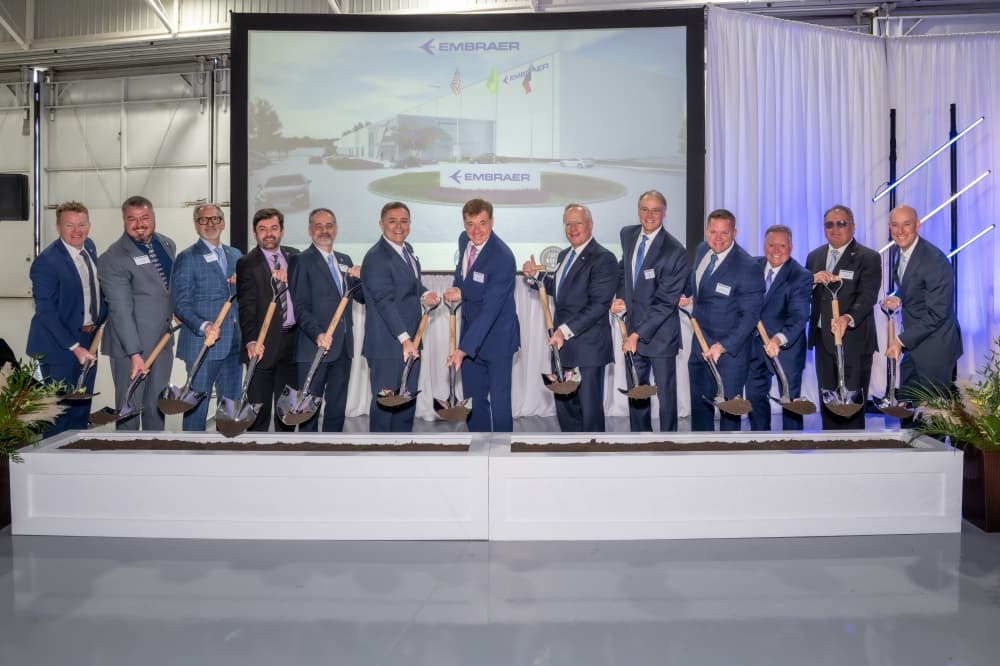 Embraer representatives digging in dirt for a groundbreaking ceremony