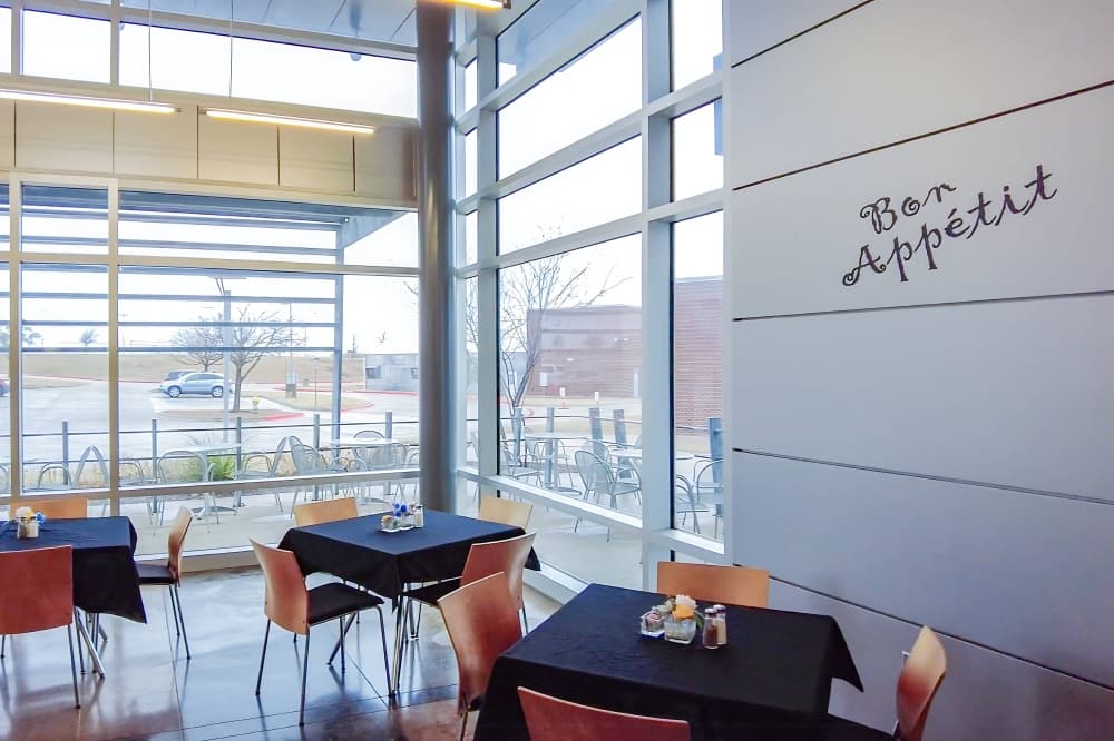 Dining room in a restaurant with windows looking out on a school building. 