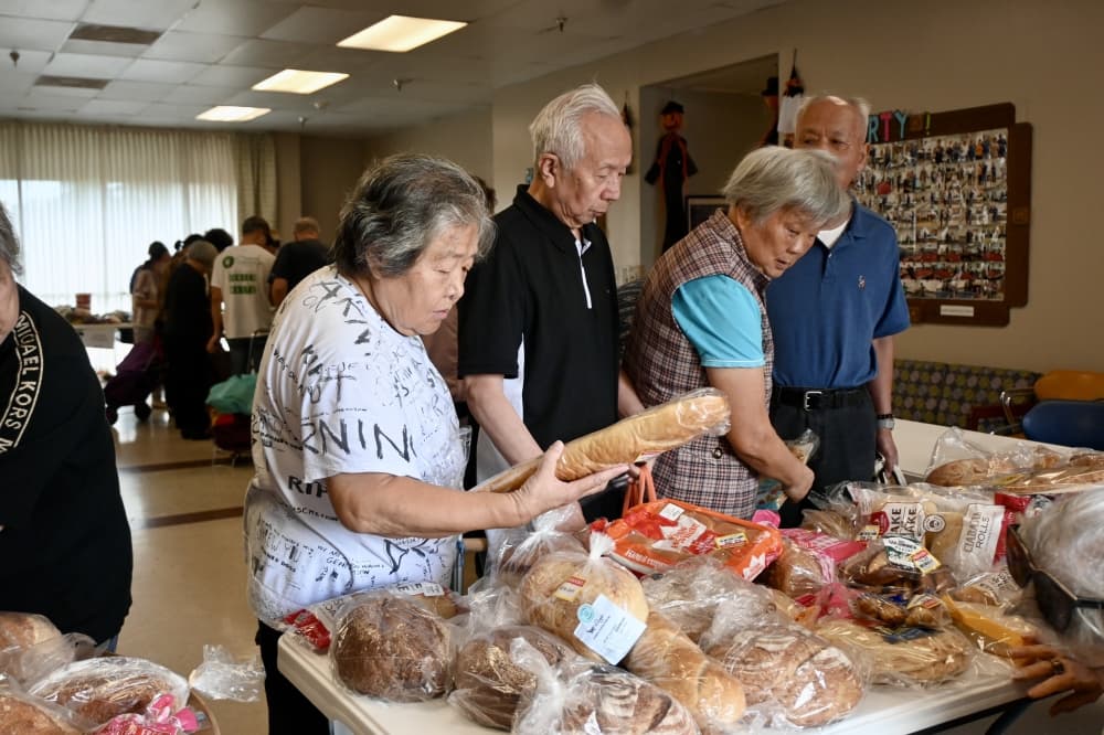 people pick up different types of bread from a table