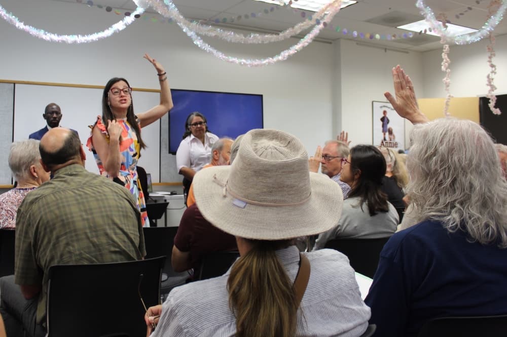 People raise there hand and a woman stands up to talk