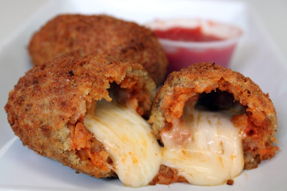Fried food items cut in half with melting mozzarella cheese. 