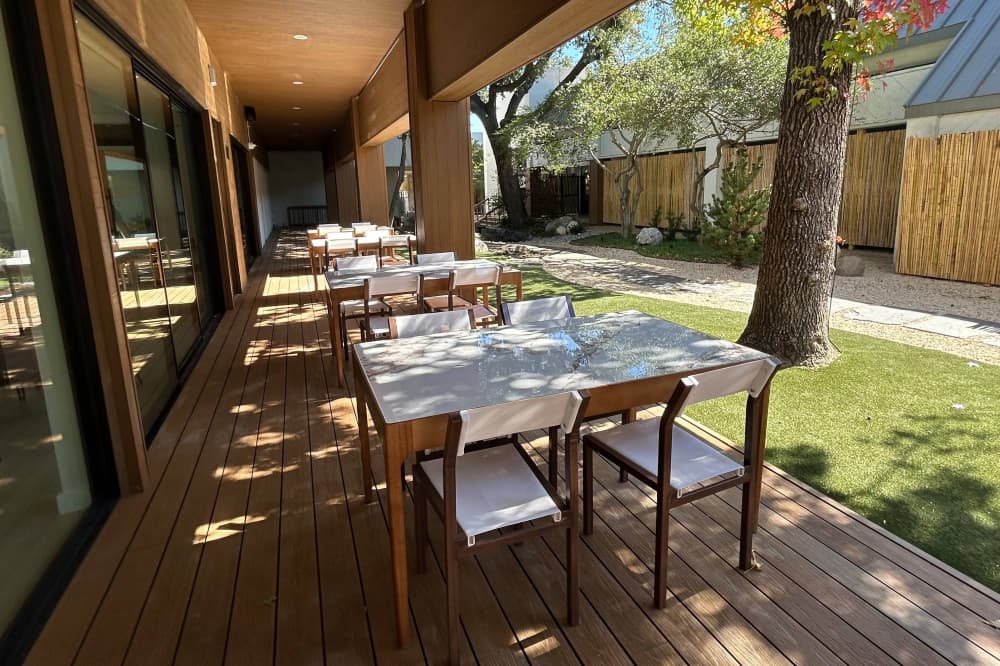 Restaurant covered patio seating next to a zen garden. 