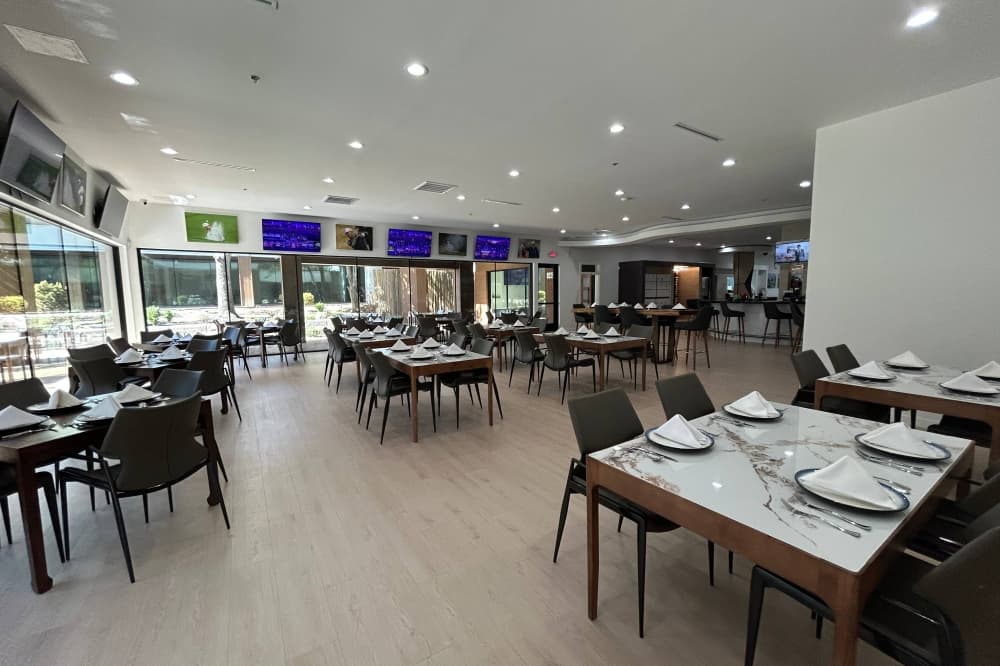 Interior of a restaurant with large picture windows lining one side of the dining room. 
