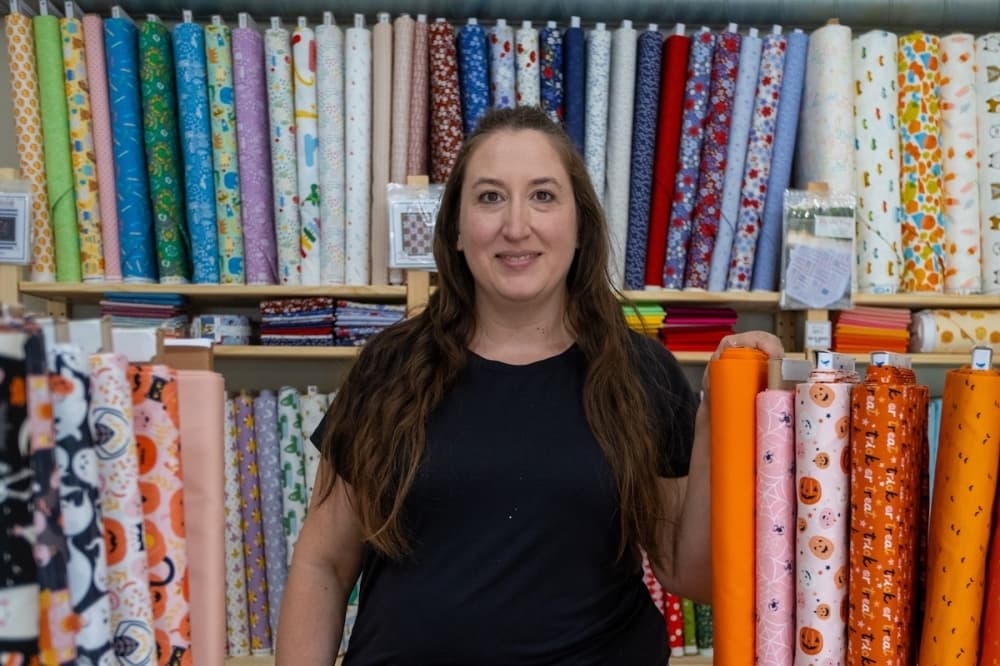 Trina Iblings, owner of Snippets, stands in front of fabric she has for sale.