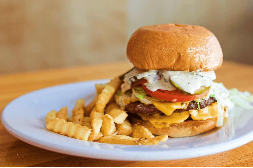 Diner Double Burger from Phoebe’s Diner in Austin, Texas — two quarter-pound beef patties on a toasted potato roll with house pickles, spinach, tomato, American cheese, onion, and special sauce, a top-rated Austin burger for brunch and comfort food lovers.