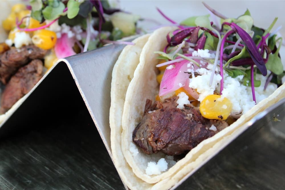 Steak tacos on a silver taco stand. 