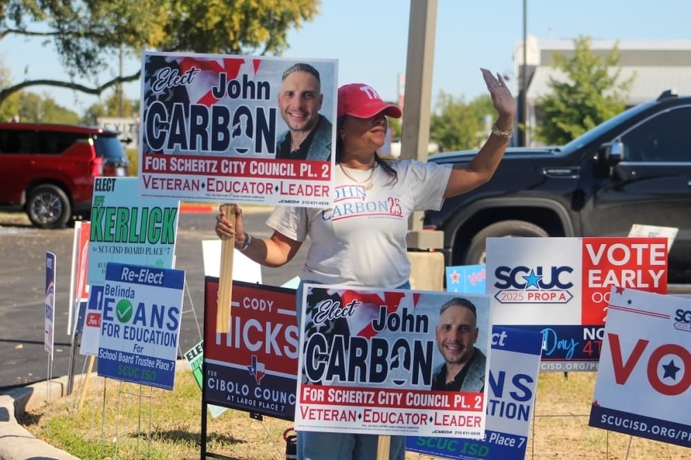 Karen Carbon holds signs supporting Schertz City Council Place 2 challenger John Carbon. (Amira Van Leeuwen/Community Impact)