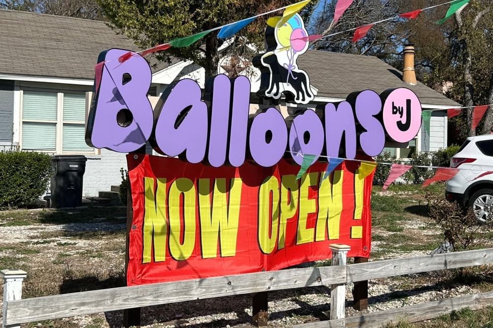 Balloons by J sign with a temporary banner stating 'now open'