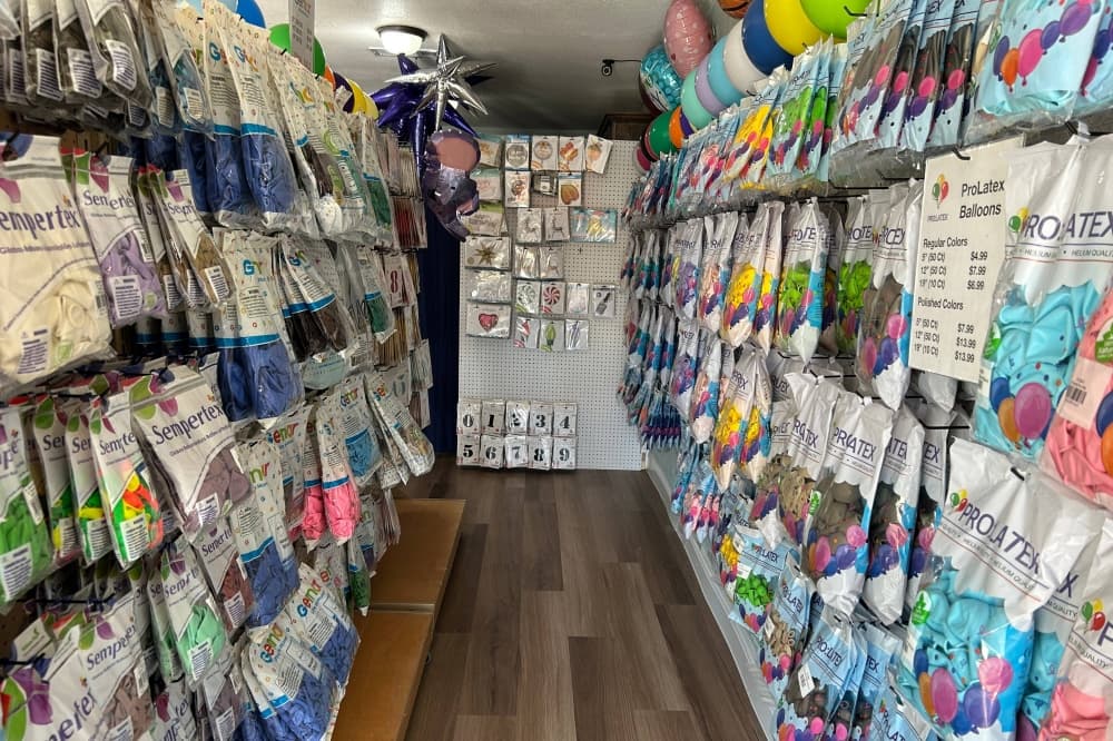 Aisle in a store with bags of deflated balloons displayed.