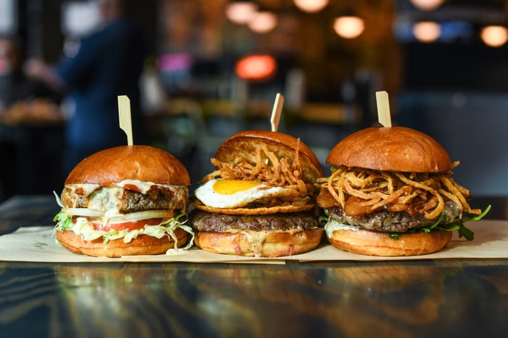 Three different types of burgers on a dish in a restaurant. 