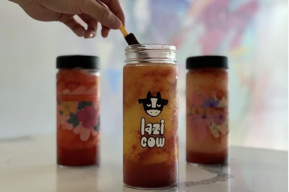 Three cups featuring Lazi Cow branding and filled with different drinks. 