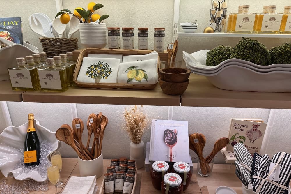 Shelf of products, such as wooden spoons, towels and perfumes.