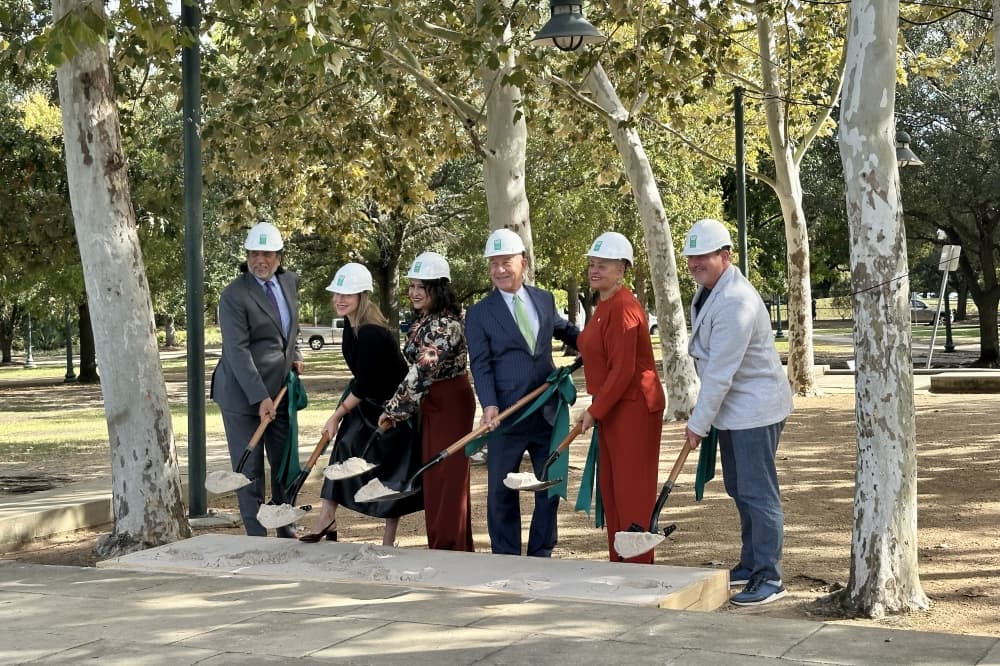 people wearing hard hats shovel gravel