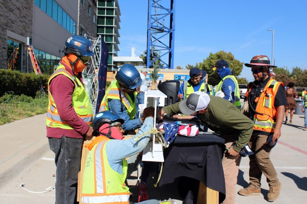 People wearing construction hard hat and vest signing a construction beam. 