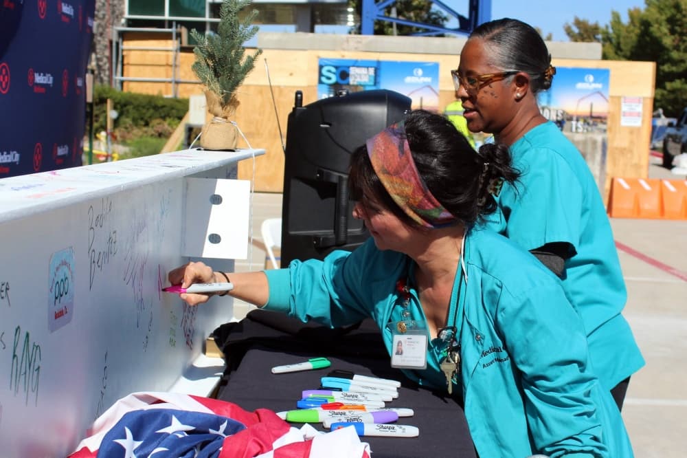 Two females signing a construction beam. 