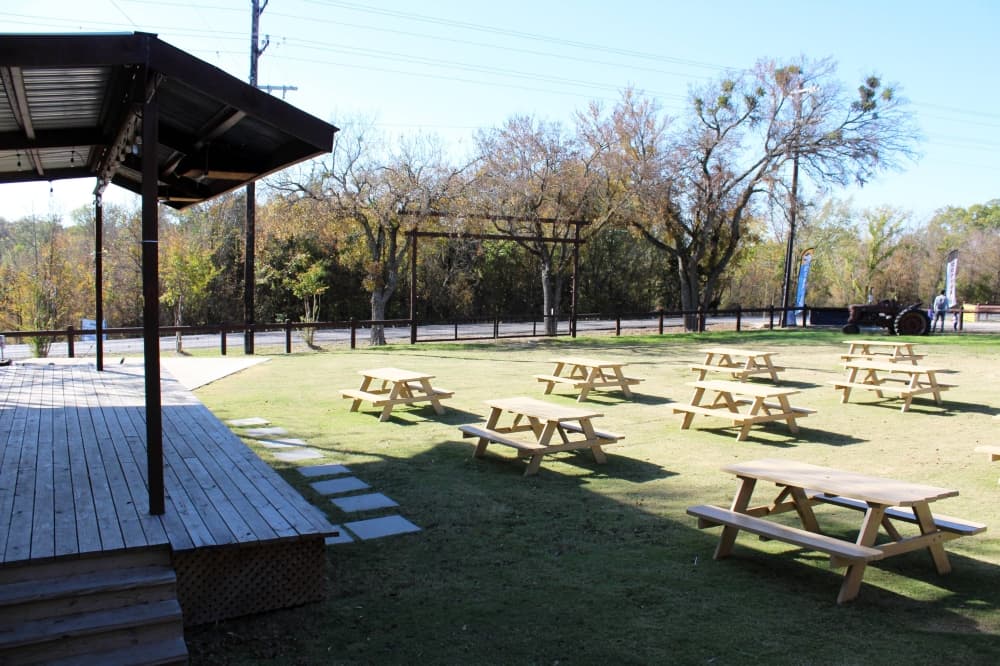Outside stage with picnic tables in front of it. 
