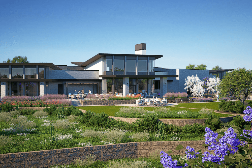 a white building with grass and flowers in the foreground