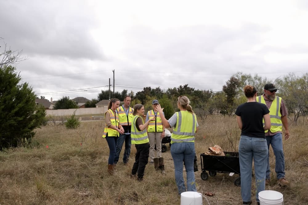people wearing neon vests in a grassy field