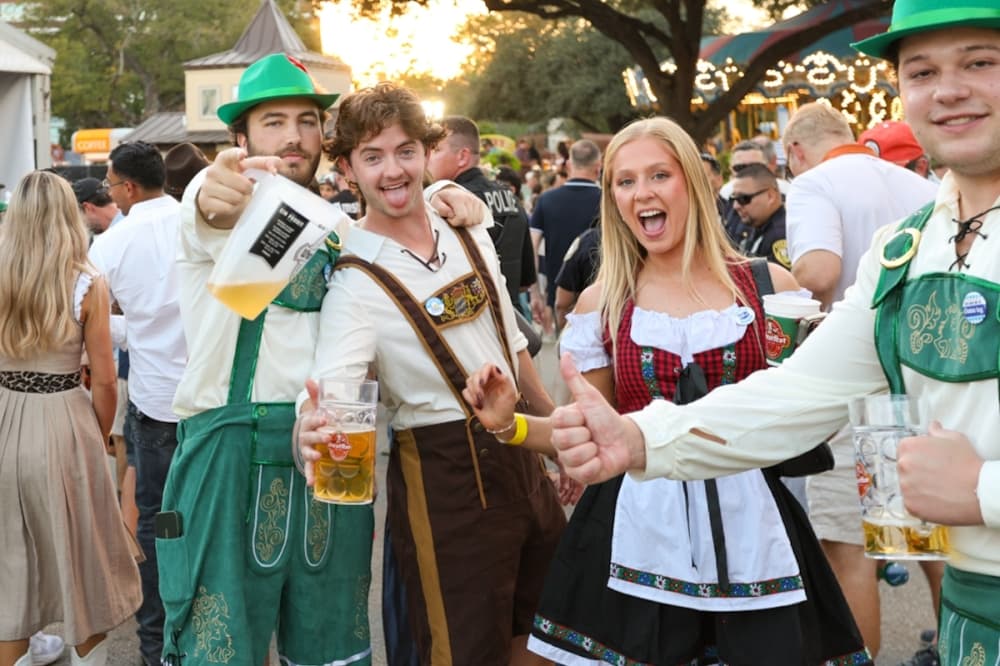 Attendees show off their German costumes and beer pitchers at Wurstfest 2025. (Ethan Thomas/Community Impact)