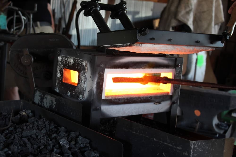 A piece of metal held by tongs in an open forge. 