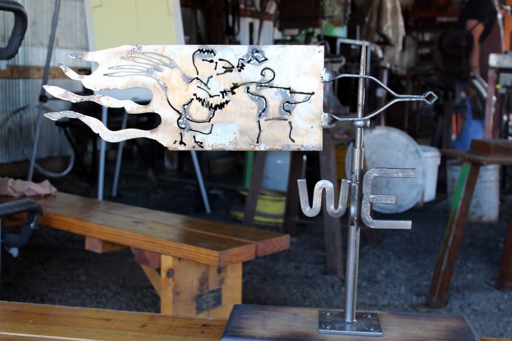 Weathervane made of metal featuring a bird etched into the metal flag portion of the vane. 