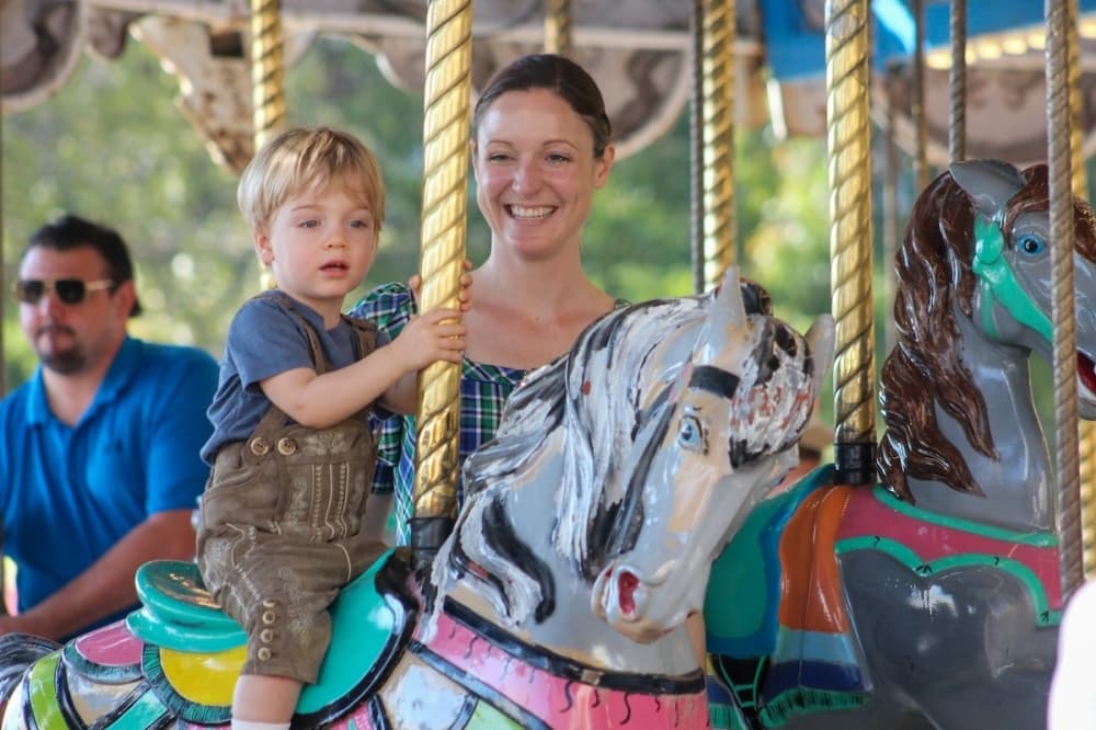 Kaci Sykora rides a carousel with her son, Dean, at Wurstfest in New Braunfels. (Amira Van Leeuwen/Community Impact)