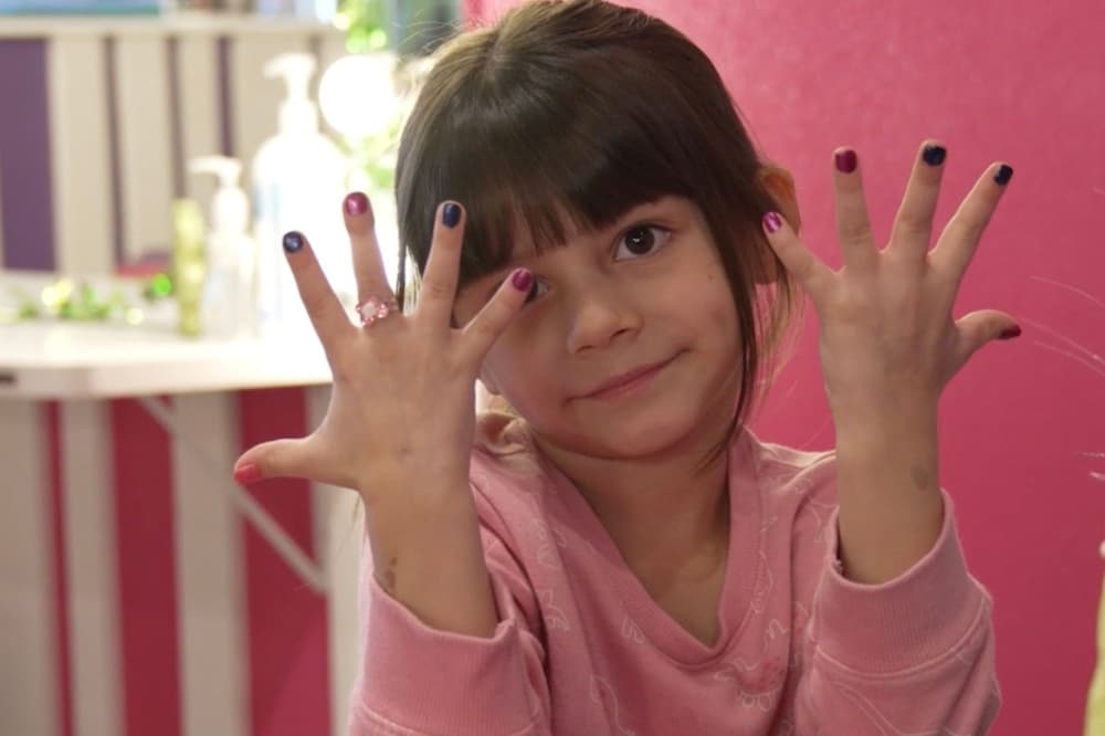 a girl holds up her hands to show polished fingernails
